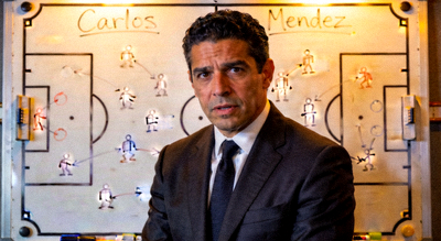 卡洛斯·门德斯 Carlos Mendez 正面肖像，身穿深色西装，背景为战术板，表情专注